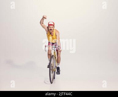 Portrait du jeune homme en vêtements colorés, vélo d'équitation uniforme isolé sur fond gris. Sportif. Pilote gagnant Banque D'Images