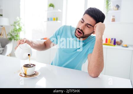 Portrait de somnolent épuisé jeune personne fermé yeux bât bras tenir verser le café renversé sur la tasse cuisine à l'intérieur Banque D'Images