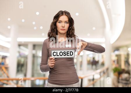 l'assistant d'atelier avec une affiche fermée montre les pouces vers le bas Banque D'Images