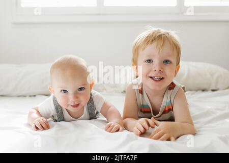 Portrait de frères (6-11 mois, 2-3) couché sur le lit Banque D'Images