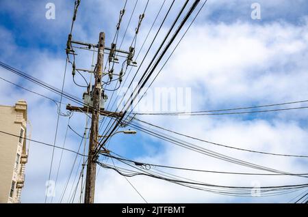 Câbles électriques aériens dans une rue de San Francisco, Californie, vus contre un ciel bleu avec des nuages. Banque D'Images