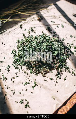 Tas d'herbes sèches sur fond de table rustique sous la lumière du soleil et l'ombre. Plantes médicinales séchées. Pile de feuilles et de fleurs hachées sur papier elle Banque D'Images