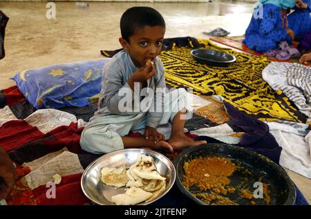 Karachi, Pakistan, 30 août 2022. Un enfant touché par les inondations mangeant un repas après avoir été accueilli dans un camp de secours d'victimes d'inondations établi dans une école gouvernementale située dans la région de Sachal Goth à Karachi mardi, 30 août 2022. Banque D'Images