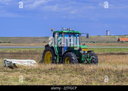 Tracteur John Deere 6400 avec faucheuse à disques fauchant de l'herbe dans les prairies/prairies en été à Waterdunen, réserve naturelle près de Breskens, Zeeland, pays-Bas Banque D'Images