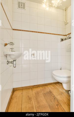 toilettes murales et petit lavabo dans la salle de toilette avec carrelage blanc Banque D'Images