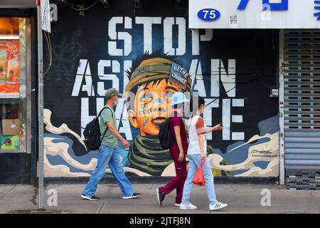 Les gens marchent devant une fresque « Top Asian Hate » dans le quartier chinois de Manhattan. L'œuvre d'art et le message peints par Dragon76, un peintre japonais à New York. Banque D'Images