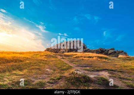 Magnifique lever de soleil sur le crag d'Almscliffe, dans le Nord du Yorkshire. Une lumière brillante et dorée brille sur l'herbe entourant le format de roche de l'affleurement des grains de meules Banque D'Images