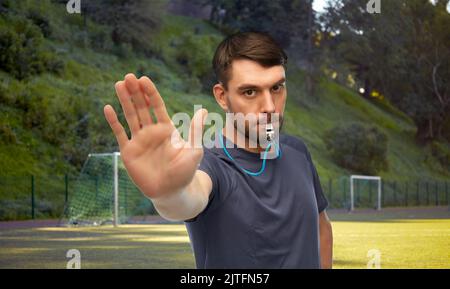 arbitre de football avec sifflet montrant un geste d'arrêt Banque D'Images