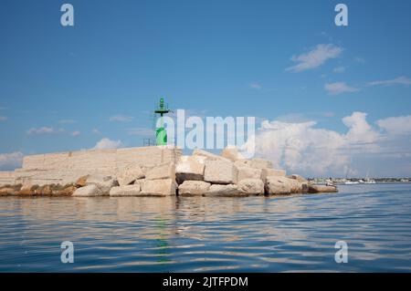 Une tour de signalisation en métal vert se dresse sur les rives de la mer Méditerranée. La tour se trouve sur de nombreux blocs de pierre. En arrière-plan le ciel bleu refl Banque D'Images