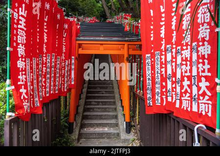 Un tunnel vif de portes rouges de Torii borde les escaliers en pierre menant au sanctuaire de HIE Jinja à Nagatacho, Chiyoda, Tokyo, Japon. Le sanctuaire Shinto est l'un des trois grands sanctuaires de Tokyo. Banque D'Images