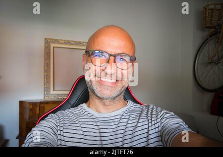 Un homme chauve heureux en lunettes prenant un selfie Banque D'Images