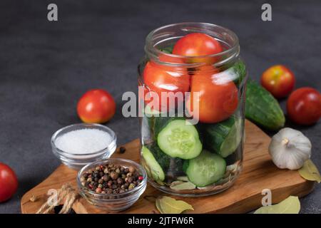 Les concombres et les tomates cerises sont placés dans un pot avec de l'ail, des feuilles de Laurier, du poivre et de l'aneth. Préparation au décapage, étape par étape Banque D'Images