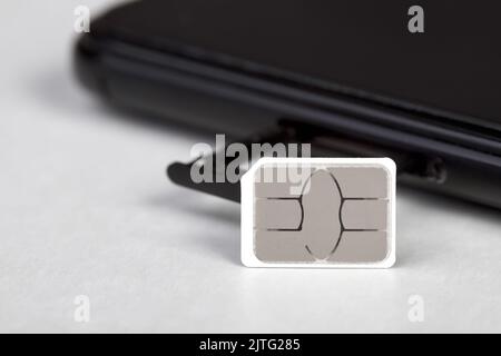 Carte SIM près du smartphone avec un plateau de carte sim ouvert sur fond clair Banque D'Images