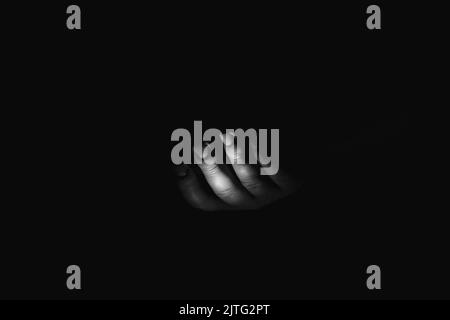 Main masculine dans la photo noire, noire et blanche, peur et horreur, une main demandant de l'aide Banque D'Images