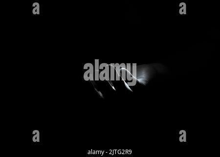 Main masculine dans la photo noire, noire et blanche, peur et horreur, une main demandant de l'aide Banque D'Images