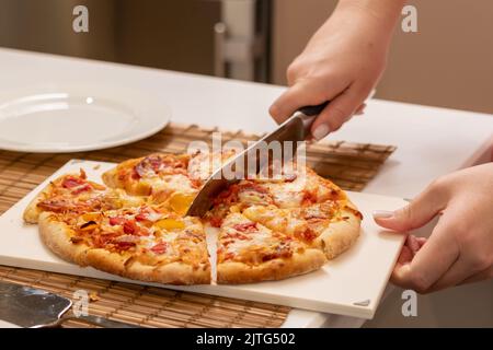 Coupe de pizza avec un grand couteau à la maison gros plan Banque D'Images