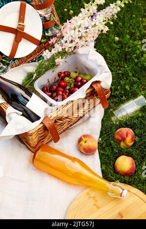 nourriture, boissons et panier sur une couverture de pique-nique sur l'herbe Banque D'Images