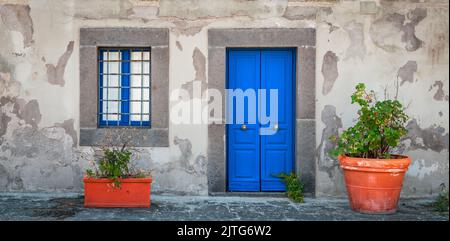 Façade avec porte et fenêtre bleues, avec plantes en pot à l'avant. Banque D'Images