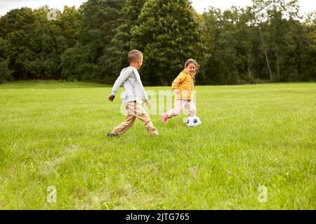 petits enfants avec le ballon jouant au football au parc Banque D'Images