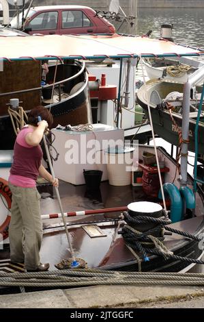 AJAXNETPHOTO. 2011. CONFLANS SAINTE HONORINE, YVELINES, FRANCE. - FORME DU NAVIRE ET - MOP EN MAIN, UNE FEMME NETTOIE LE PONT D'UNE PENICHE AMARRÉE DANS LE PORT. PHOTO:JONATHAN EASTLAND/AJAX REF:D112603 1071 Banque D'Images