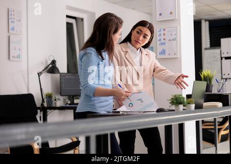 Les employés analysent la recherche, discutent de rapport financier, parlent de statistiques. Démarrez les employés de l'entreprise discutant du plan stratégique, les femmes travaillant dans l'espace de travail des collègues Banque D'Images