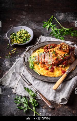 Jarret de veau et os avec polenta et légumes sur l'assiette de service avec garniture aux herbes Banque D'Images