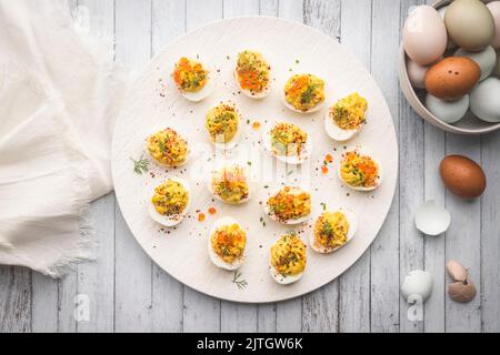 Œufs déroulés sur un plateau blanc avec caviar et un bol d'œufs de couleur pâle Banque D'Images