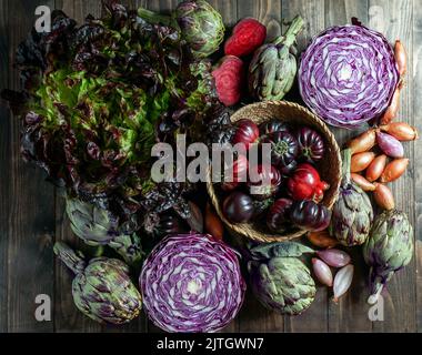 légumes violets sur fond de bois, artichaut violet, tomates, oniones, salade Banque D'Images