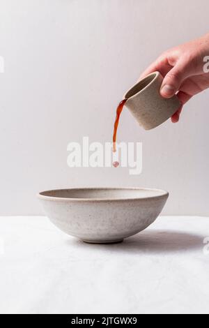 Versez à la main la verseuse de café dans un bol en céramique. Banque D'Images