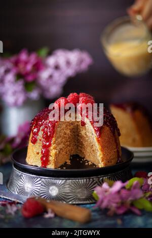 Un pudding en éponge cuit à la vapeur recouvert de confiture de framboise avec une tranche retirée. Banque D'Images