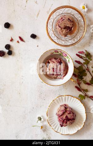 Boules de mûre et glace au chocolat dans des bols et des tasses de thé. Banque D'Images