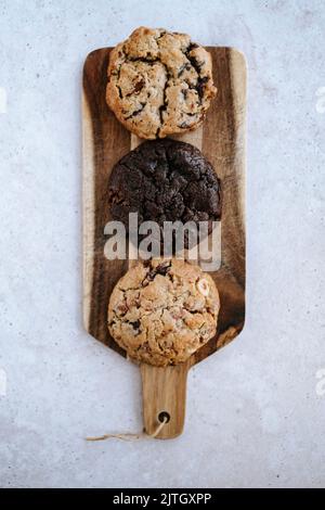 variété de 3 biscuits, placés sur une assiette en bois, sur fond gris Banque D'Images
