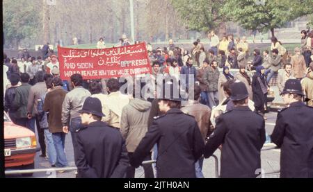 30 avril 1980, Londres, Royaume-Uni: Les partisans iraniens portant une grande bannière de protestation défilant à Londres pendant le siège de six jours de l'ambassade iranienne. Du 30 avril au 5 mai 1980, un groupe de six dissidents iraniens armés, opposés à l'ayatollah Khomeini, le chef religieux arrivé au pouvoir en 1979, a pris la relève de l'ambassade iranienne à la porte du Prince à South Kensington, à Londres. Le groupe iranien a pris 21 otages, dont deux ont été tués. Près de la scène du siège, les partisans de Khomeini ont fait connaître leur point de vue par une protestation. Le spectaculaire siège de six jours s'est terminé lorsque les troupes d'élite britanniques SAS ont été déployées Banque D'Images