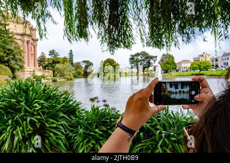 Une dame prend une photo du Palais des Beaux-Arts de San Francisco, en Californie, avec la rotonde, le lac et la fontaine en vue. Banque D'Images