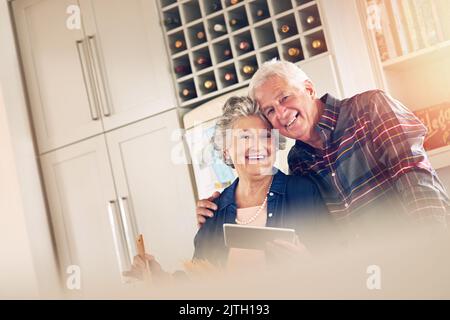 Pour moi, c'est toujours la femme la plus belle et la plus étonnante. Portrait d'un couple senior utilisant une tablette numérique tout en cuisant ensemble dans leur cuisine à Banque D'Images