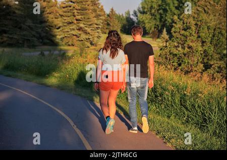 Couple d'âge mûr marchant au coucher du soleil sur la route Banque D'Images