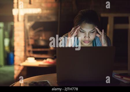 Depuis trop longtemps, Shes a dû faire face au même problème. Un jeune entrepreneur qui cherche à se stresser tout en travaillant tard sur un ordinateur portable dans un atelier. Banque D'Images