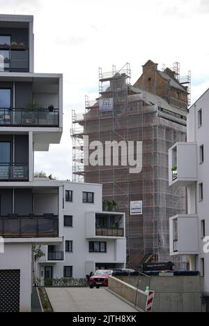 Oranienburg, Allemagne. 29th août 2022. L'ancien grenier d'Oranienburg est visible entre des immeubles d'appartements blancs récemment construits sur Louise-Henriette-Steg. L'échafaudage est d'environ 35 mètres de haut et se trouve sur la liste des monuments de l'état de Brandebourg. Après la destruction du premier grenier par un incendie majeur en 1916, le nouveau bâtiment a été érigé un an plus tard, l'un des premiers bâtiments en béton armé dans la région. Crédit : Soeren Stache/dpa/Alay Live News Banque D'Images