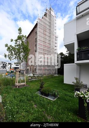 Oranienburg, Allemagne. 29th août 2022. L'ancien grenier d'Oranienburg peut être vu à côté de nouveaux immeubles d'appartements blancs sur Louise-Henriette-Steg. L'échafaudage est d'environ 35 mètres de haut et se trouve sur la liste des monuments de l'état de Brandebourg. Après la destruction du premier grenier par un incendie majeur en 1916, le nouveau bâtiment a été érigé un an plus tard, l'un des premiers bâtiments en béton armé dans la région. Crédit : Soeren Stache/dpa/Alay Live News Banque D'Images