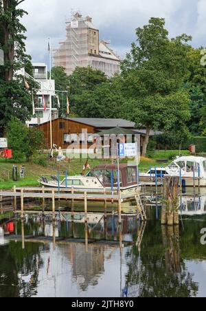 Oranienburg, Allemagne. 29th août 2022. L'ancien grenier d'Oranienburg peut être vu derrière la Havel et des arbres près de la Louise-Henriette-Steg. Le bâtiment d'échafaudage est d'environ 35 mètres de haut et est sur la liste des monuments de l'état de Brandebourg. Après la destruction du premier grenier par un incendie majeur en 1916, le nouveau bâtiment a été érigé un an plus tard, l'un des premiers bâtiments en béton armé dans la région. Crédit : Soeren Stache/dpa/Alay Live News Banque D'Images