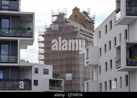 Oranienburg, Allemagne. 29th août 2022. L'ancien grenier d'Oranienburg est visible entre des immeubles d'appartements blancs récemment construits sur Louise-Henriette-Steg. L'échafaudage est d'environ 35 mètres de haut et se trouve sur la liste des monuments de l'état de Brandebourg. Après la destruction du premier grenier par un incendie majeur en 1916, le nouveau bâtiment a été érigé un an plus tard, l'un des premiers bâtiments en béton armé dans la région. Crédit : Soeren Stache/dpa/Alay Live News Banque D'Images