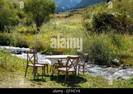 table et chaises en bois au bord de la rivière de montagne Banque D'Images