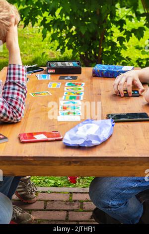 Gros plan, mains de père et de fils jouant à des jeux de société sur la terrasse confortable de maison de campagne sur une table en bois contre la verdure floue. Journée de l'amitié, Fathe Banque D'Images