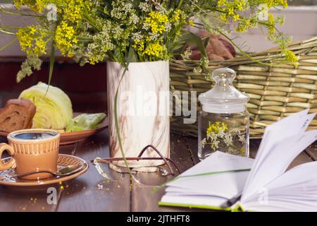 petit-déjeuner avec thé frais, pain de seigle, fromage et herbes, fleurs sauvages à l'extérieur sur la terrasse agréable de la maison de campagne ou cottage. attention sélective. gros plan li Banque D'Images