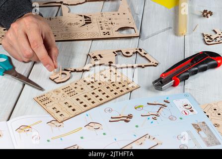 Père concentré de fabrication de jouets en bois dans le cadre de travaux de bricolage. Homme main assemblage du bois, travail de bricolage en bois, gros plan. Les mains de l'homme font l'artisanat à partir de bois. Comme Banque D'Images