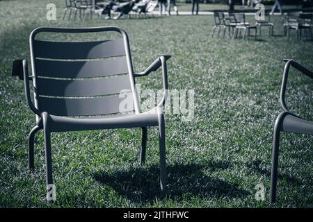 chaise de patio debout sur l'herbe de pelouse vide et entretenue au crépuscule. Profondeur de champ réduite. Concept de dépression de solitude maladie et mort Banque D'Images