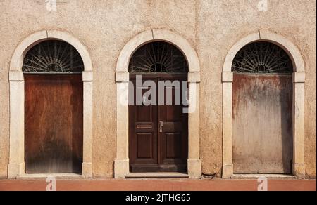 Mur en pierre avec trois portes voûtées. Porte en bois d'époque, vue avant Banque D'Images