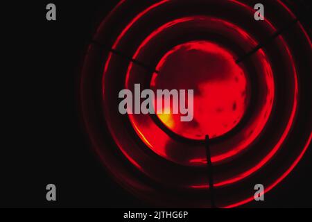 La lumière rouge du phare brille dans l'obscurité derrière une lentille de Fresnel. Résumé photo d'arrière-plan floue Banque D'Images