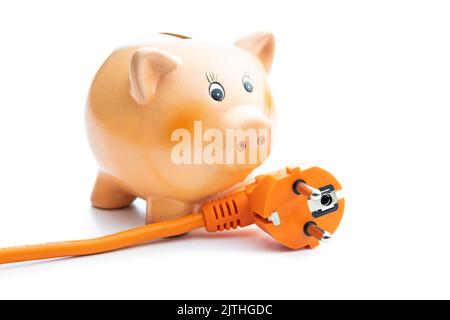 Cordon d'alimentation d'extension orange et banc de porc isolés sur fond blanc. Concept d'augmentation des prix de l'électricité. Banque D'Images