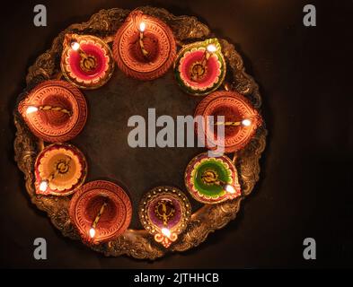 Deepavali Diwali, festival hindou des lumières. Lampe à huile de diya allumée sur Puja thali traditionnel, vue de dessus. Banque D'Images